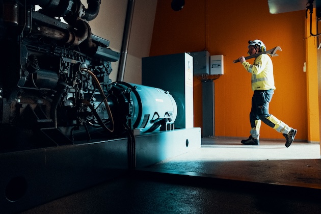 En mann med en stor skiftenøkkel går i et rom med en generator